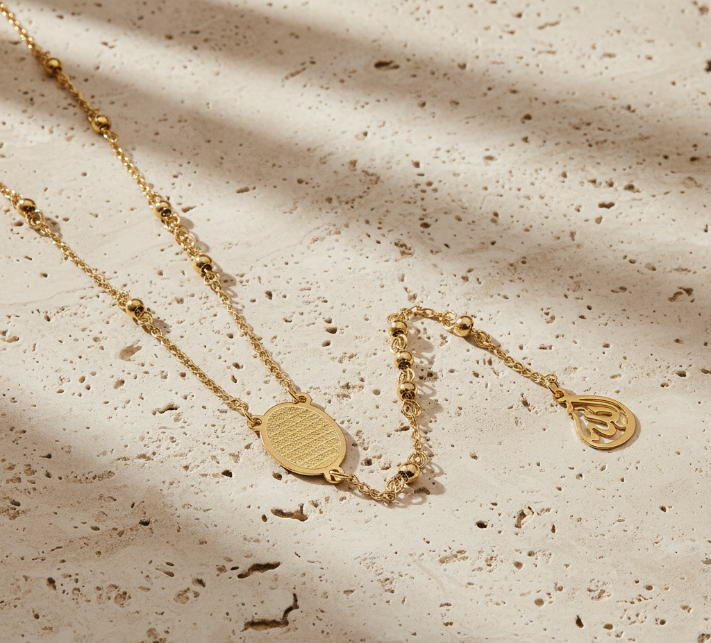 Gold necklace and bracelet on a textured beige surface