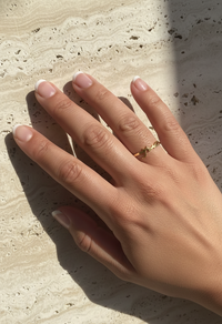 Hand wearing a gold ring on a textured stone surface