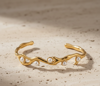 Gold bracelet with pearls on a beige background